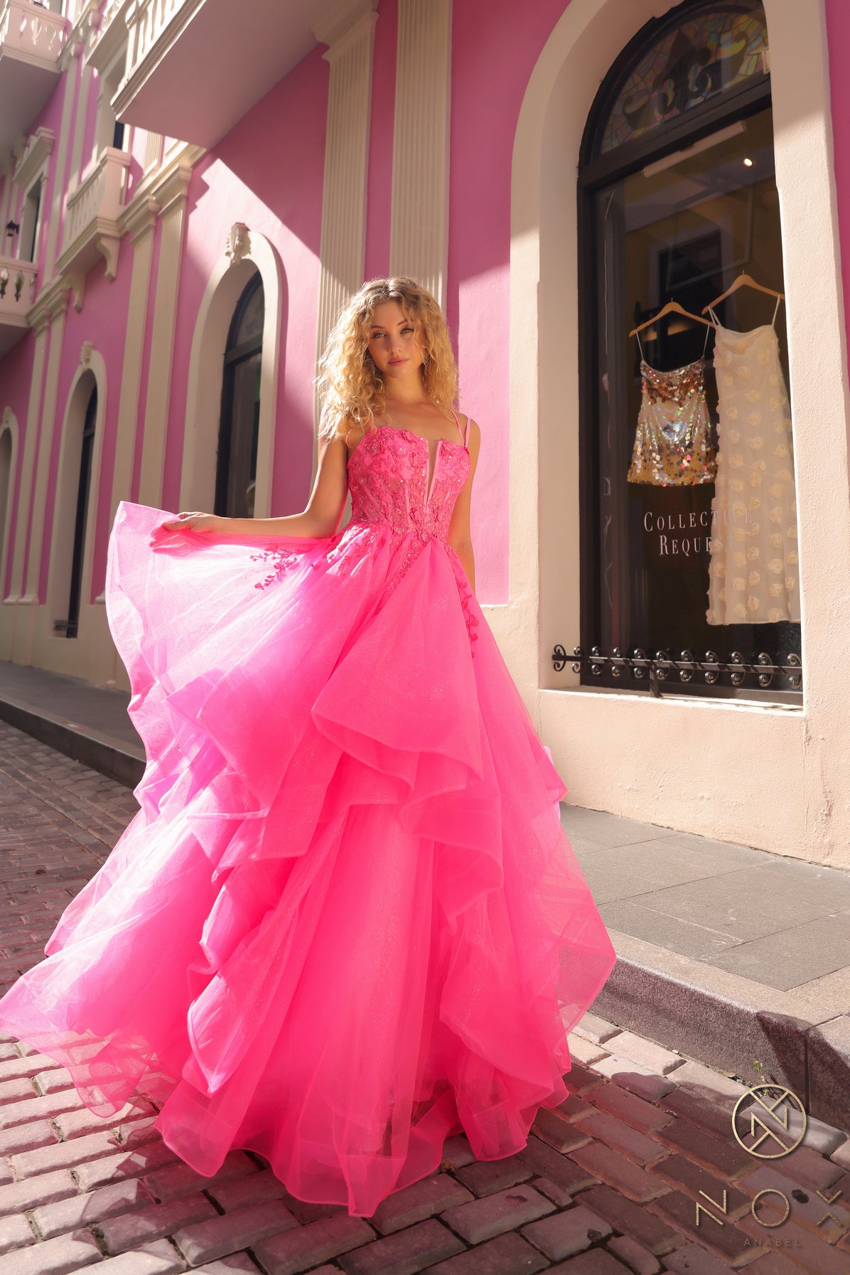 This Nox Anabel H1351 Prom Dress is the perfect combination of elegance and flair. Designed with a shimmering ruffle ballgown and a sheer sequin corset, this dress will make you stand out at any formal event. The v neck adds a touch of sophistication, making you feel like royalty.  Sizes: 0-16  Colors: Hot Pink, Lilac, Orange, Periwinkle, Royal Blue