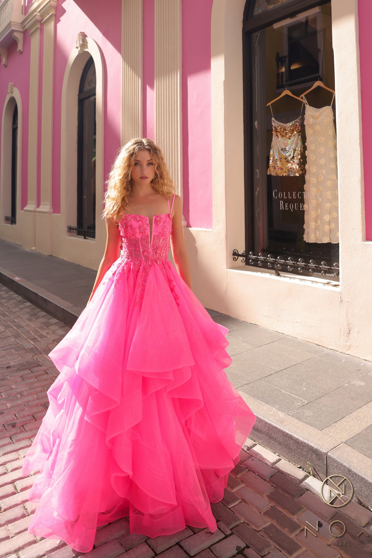 This Nox Anabel H1351 Prom Dress is the perfect combination of elegance and flair. Designed with a shimmering ruffle ballgown and a sheer sequin corset, this dress will make you stand out at any formal event. The v neck adds a touch of sophistication, making you feel like royalty.  Sizes: 0-16  Colors: Hot Pink, Lilac, Orange, Periwinkle, Royal Blue