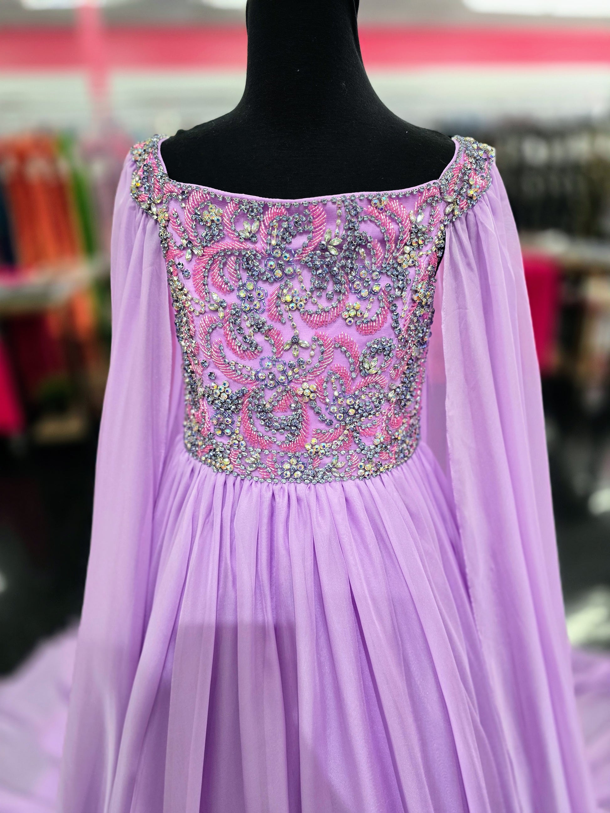 The Samantha Blade 1022 Girls Pageant Dress is the perfect choice for your little one's big day. With a stunning beaded crystal bodice and off-the-shoulder cape sleeves, she'll shine like a star. The chiffon ballgown train adds a touch of elegance and ensures she'll make a grand entrance.