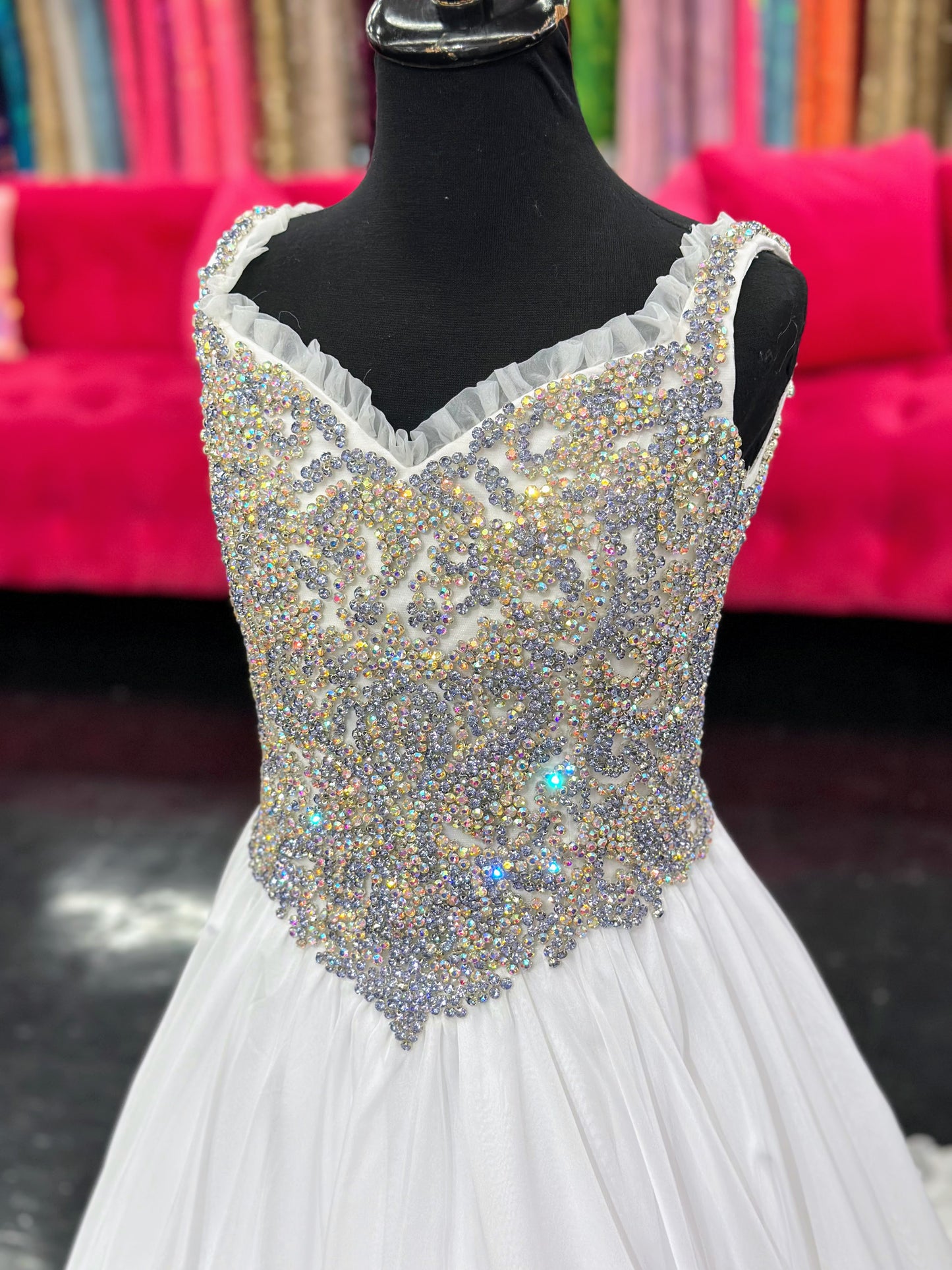 Experience the luxurious elegance of the Samantha Blake 1127 Pageant Dress. Made with soft, lightweight chiffon, this A-line ballgown will have your little girl feeling like a true princess. The crystal embellished bodice and ruffle trim neckline add a touch of sparkle and charm. Perfect for any pageant or special occasion.