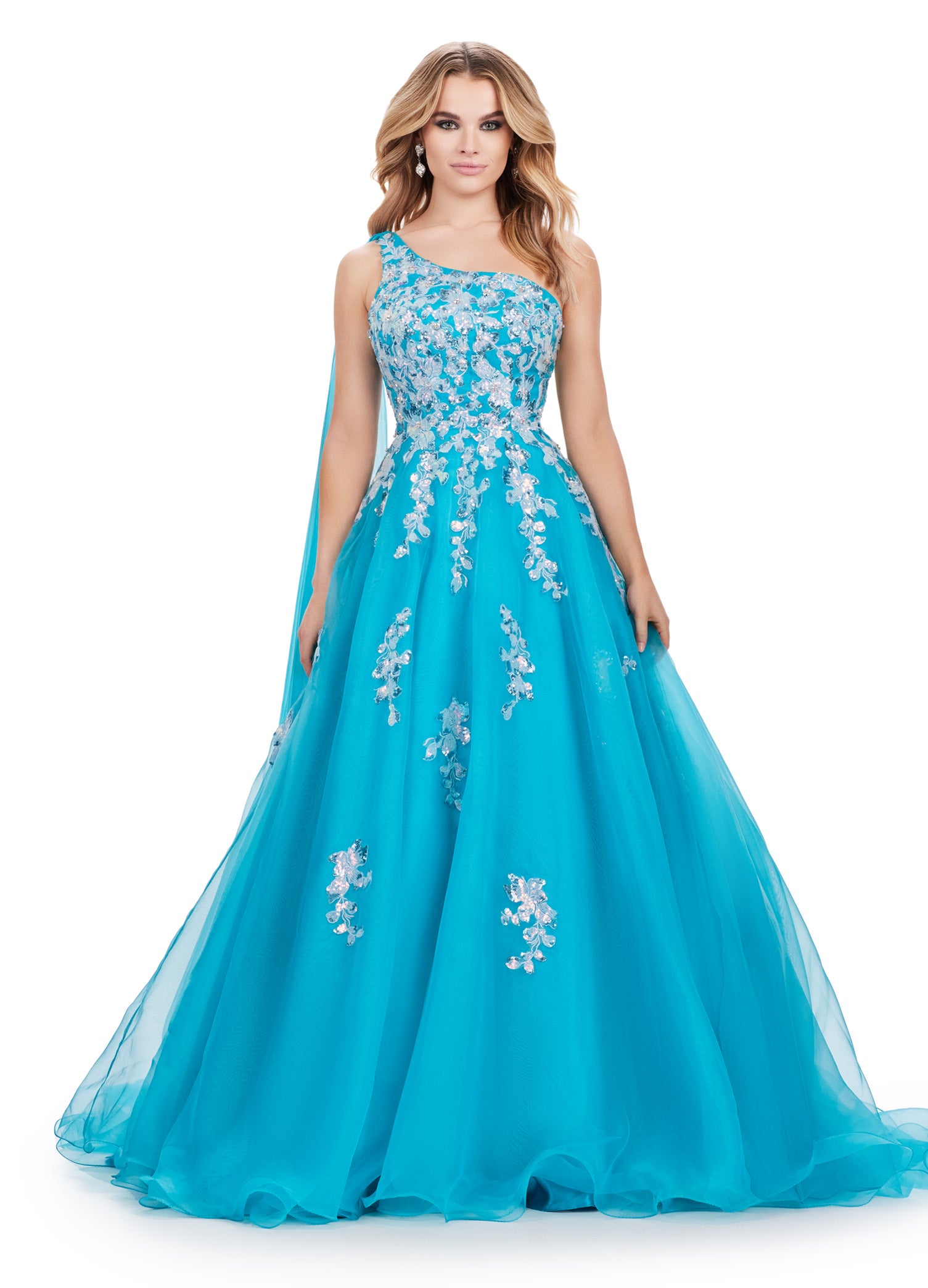 This Ashley Lauren 11573 Long Prom Dress exudes elegance with its one shoulder design and sequin applique. Crafted from high-quality organza, this gown will make you stand out at any formal event or pageant. Its classic silhouette and sparkling details are perfect for making a statement. This romantic one shoulder organza ball gown features intricate sequin applique. The look is complete with an open back and a one shoulder cape.