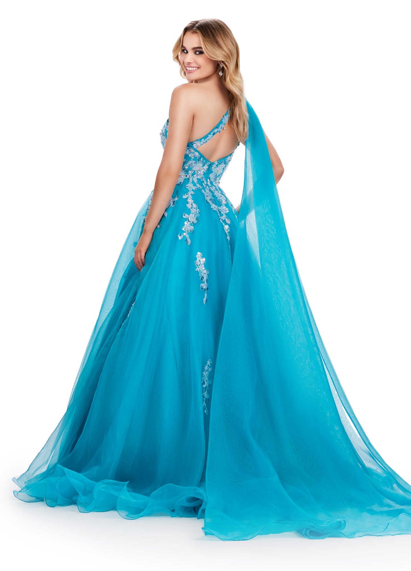 This Ashley Lauren 11573 Long Prom Dress exudes elegance with its one shoulder design and sequin applique. Crafted from high-quality organza, this gown will make you stand out at any formal event or pageant. Its classic silhouette and sparkling details are perfect for making a statement. This romantic one shoulder organza ball gown features intricate sequin applique. The look is complete with an open back and a one shoulder cape.