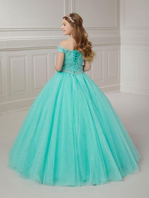 The Tiffany Princess 13722 pageant dress is a stunning option for any young contestant. The crystal and pearl bodice adds a touch of elegance, while the off-the-shoulder neckline and A-line ballgown silhouette create a regal look. Made with tulle, this dress is sure to stand out on stage. <span data-mce-fragment="1">Feel like a princess in this off-the-shoulder neckline with pearls and rhinestone beaded bodice, layers of tulle ball gown skirt and lace-up back closure.</span>