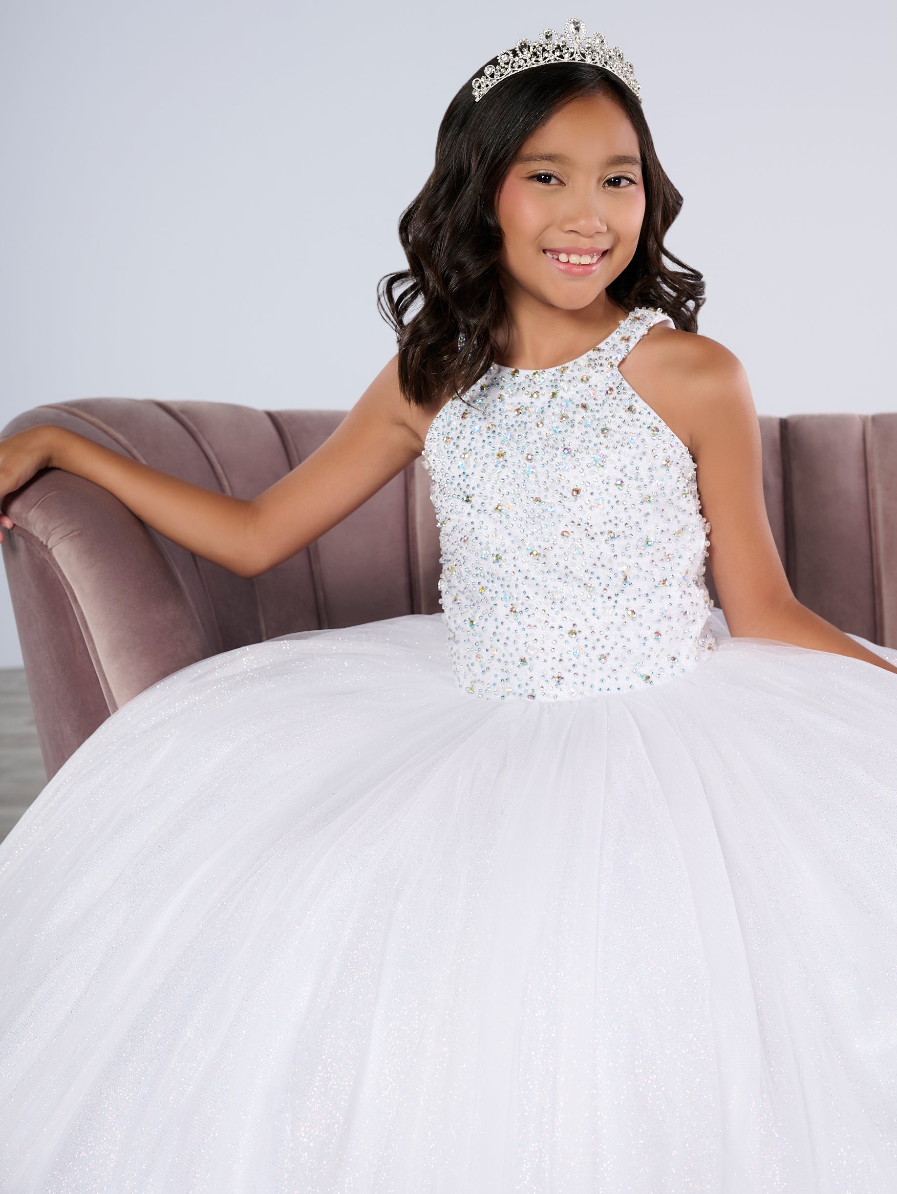 This Tiffany Princess pageant dress (style 13795) features a high neck, crystal embellishments, and a backless corset. The ruffle tulle skirt adds a touch of elegance, while the corset provides a secure fit. Perfect for any pageant girl looking to make a statement on stage.