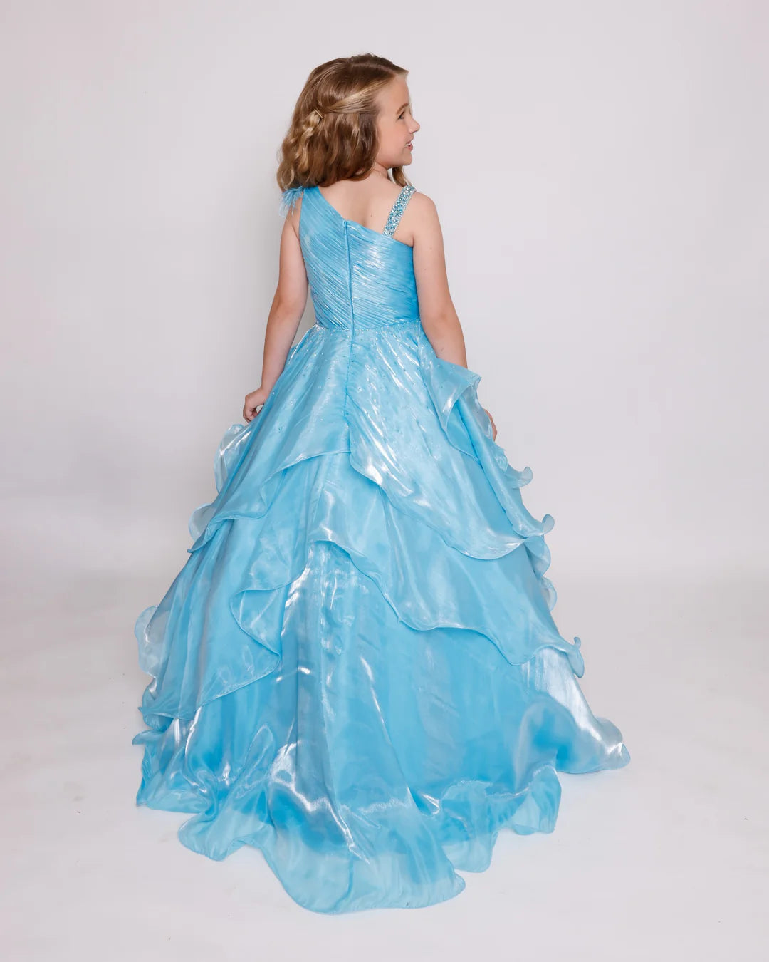 Expertly crafted for your little pageant princess, the Ava Presley Girls 39887 Long Shimmer Layer Pageant Dress is adorned with elegant feathers and crystal accents. Its one shoulder design adds a touch of sophistication to this stunning gown. She'll shine on stage with confidence and grace.