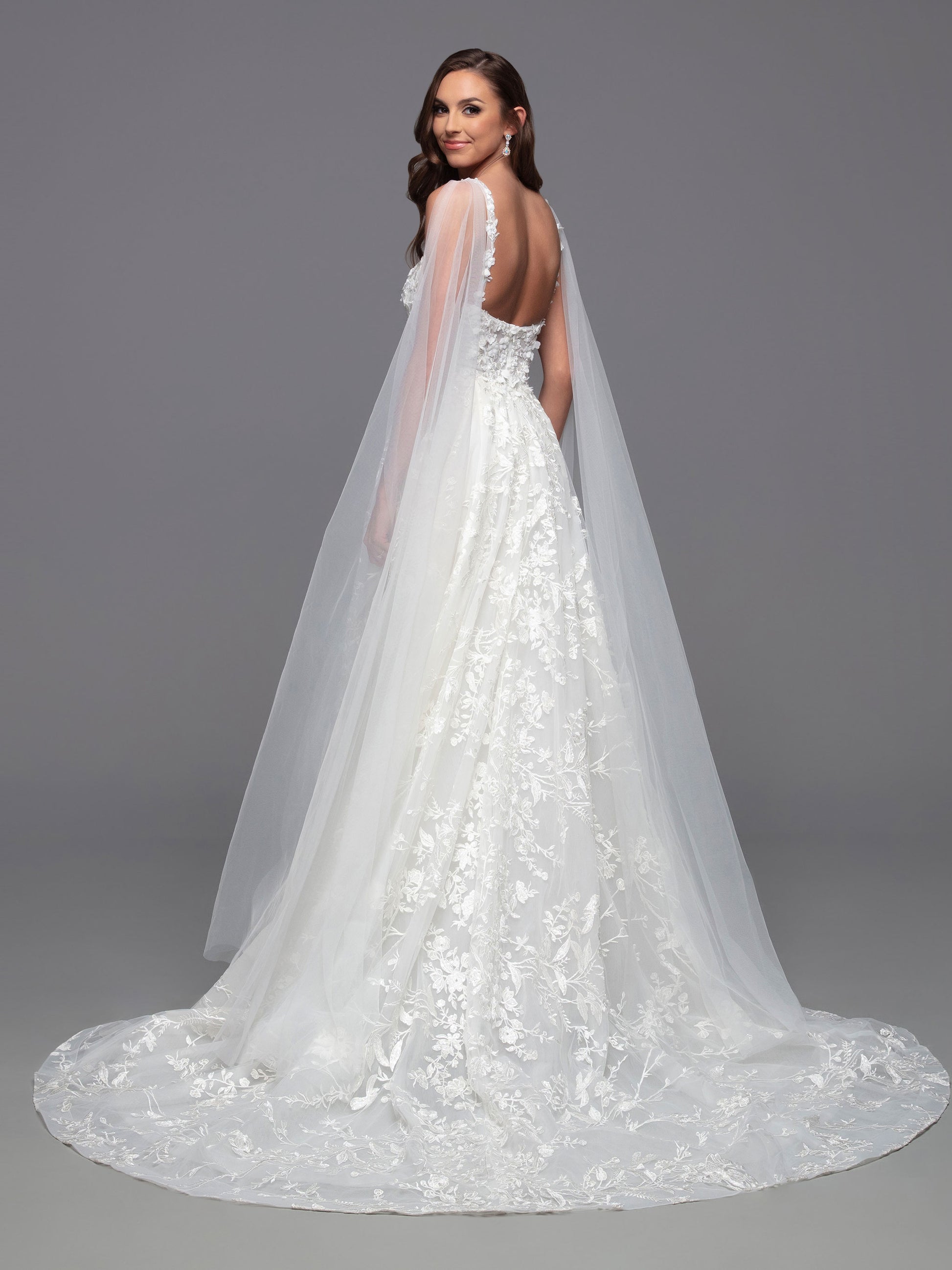 Look stunning on your special day in this Davinci Bridal 50806 A Line Lace Cape Wedding Dress. Constructed with a sheer crystal plunging neckline and 3D floral embroidery on the front and back bodice, this gown provides an exquisite look with gathered skirt and chapel train. Plus, you can customize your look and stand out in photos with the addition of the detachable veil wings.  Sizes: 2-20  Colors: Ivory