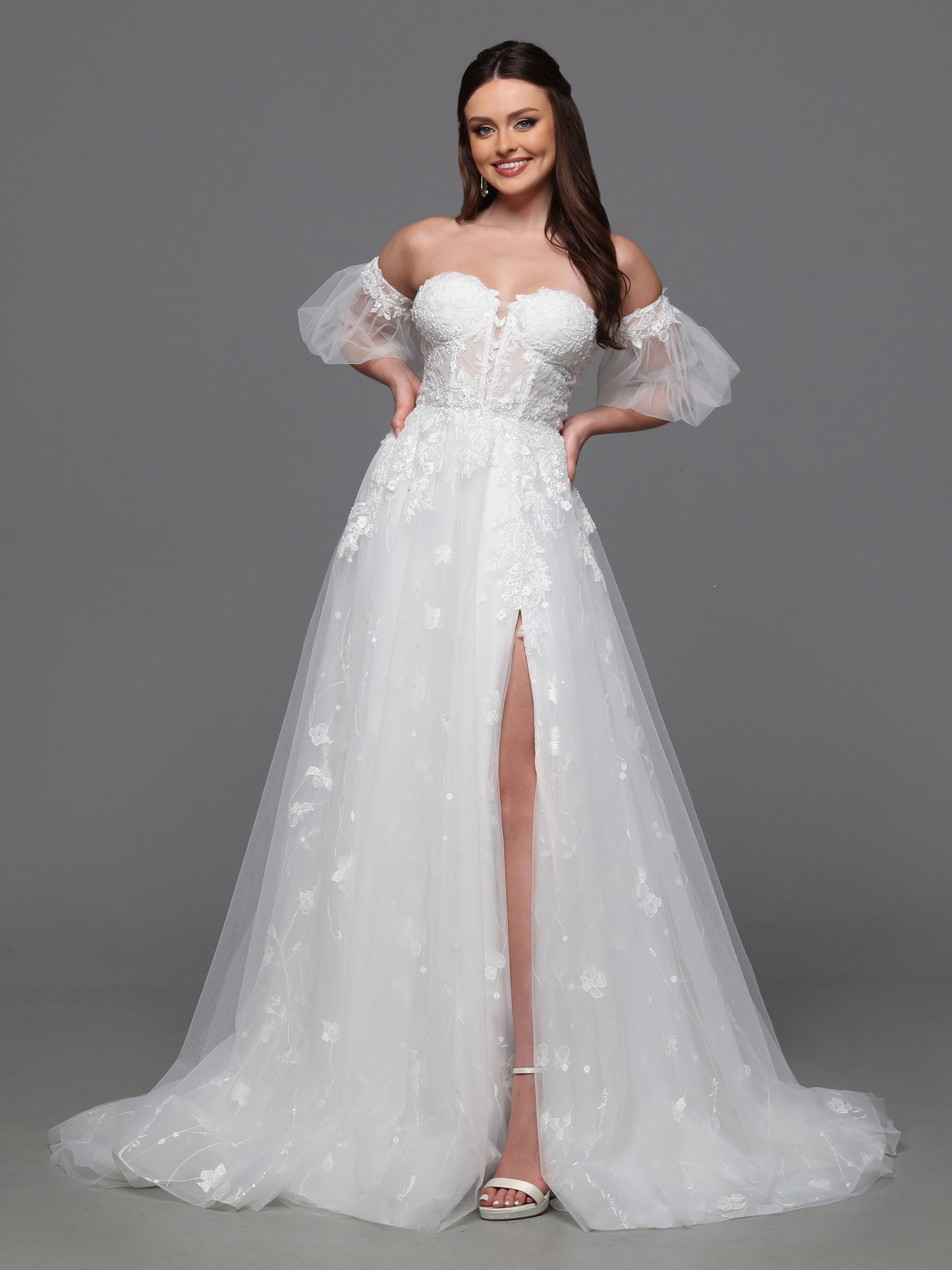 Make a statement on your special day with the Davinci Bridal 50836 A line Puff Sleeve Wedding Dress. The sheer corset enhances your silhouette while the beaded accents add a touch of glamour. With a slit for effortless movement and luxurious puddle sleeves, this dress exudes elegance and sophistication. Flirty and fashionable, this ball gown wedding dress has a sheer lace bodice, peek-a-boo slit skirt and delicate detachable sleeves.