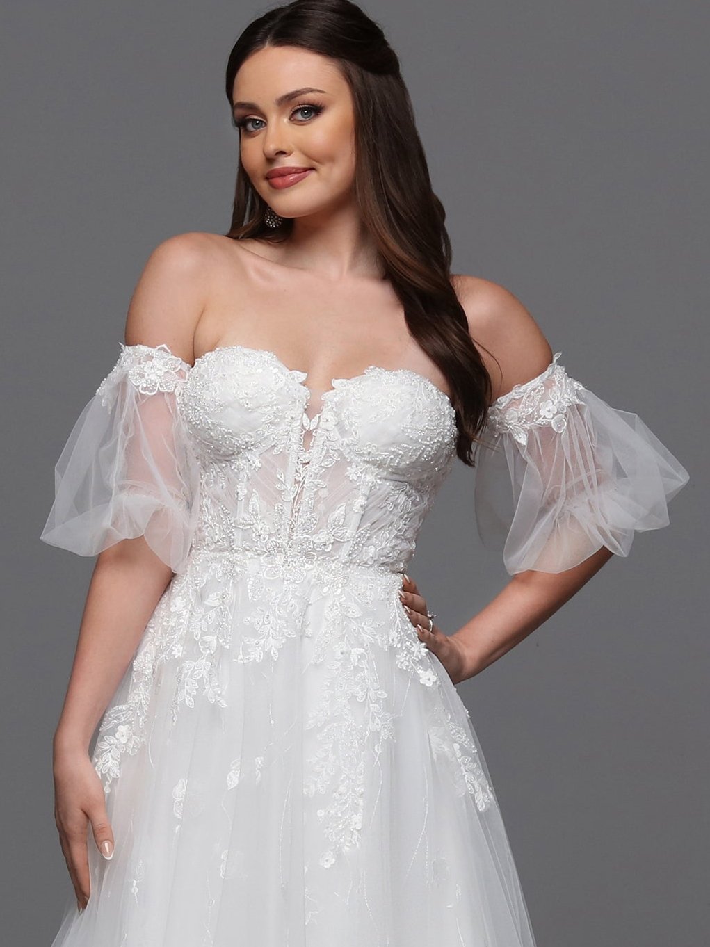 Make a statement on your special day with the Davinci Bridal 50836 A line Puff Sleeve Wedding Dress. The sheer corset enhances your silhouette while the beaded accents add a touch of glamour. With a slit for effortless movement and luxurious puddle sleeves, this dress exudes elegance and sophistication. Flirty and fashionable, this ball gown wedding dress has a sheer lace bodice, peek-a-boo slit skirt and delicate detachable sleeves.