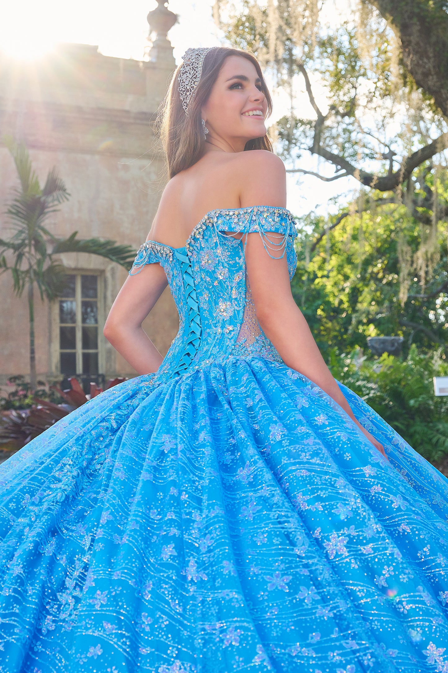 Be the belle of the ball in the Amarra 54220 Quinceanera Ball Gown. This stunning formal dress features a sheer crystal lace train and fringe, for a unique and eye-catching look. The off the shoulder design adds a touch of elegance and the perfect amount of skin. Stand out in style. Unleash your inner princess with our enchanting lace ball gown! Crafted with a dreamy lace fabric adorned with detailed floral pattern