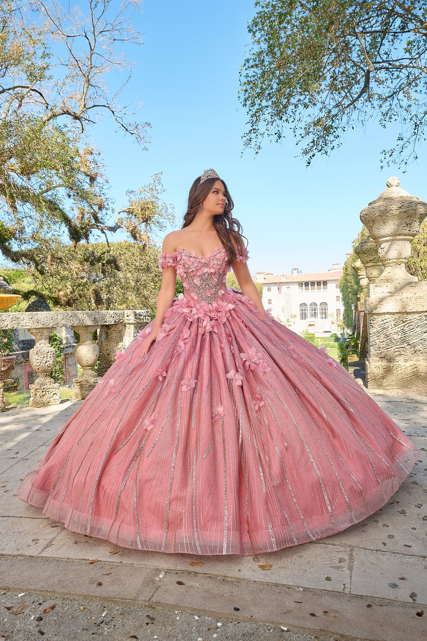 Turn heads and capture hearts in this Amarra 54226 breathtakingly whimsical ball gown! Crafted with exquisite layers of frayed tulle, this full-length dress boasts a feathery, dimensional look that's sure to enchant. The semi-sweetheart neckline paired with charming off-the-shoulder sleeves creates a delicate, feminine frame, accentuated by a fitted waistline that beautifully defines your silhouette. 