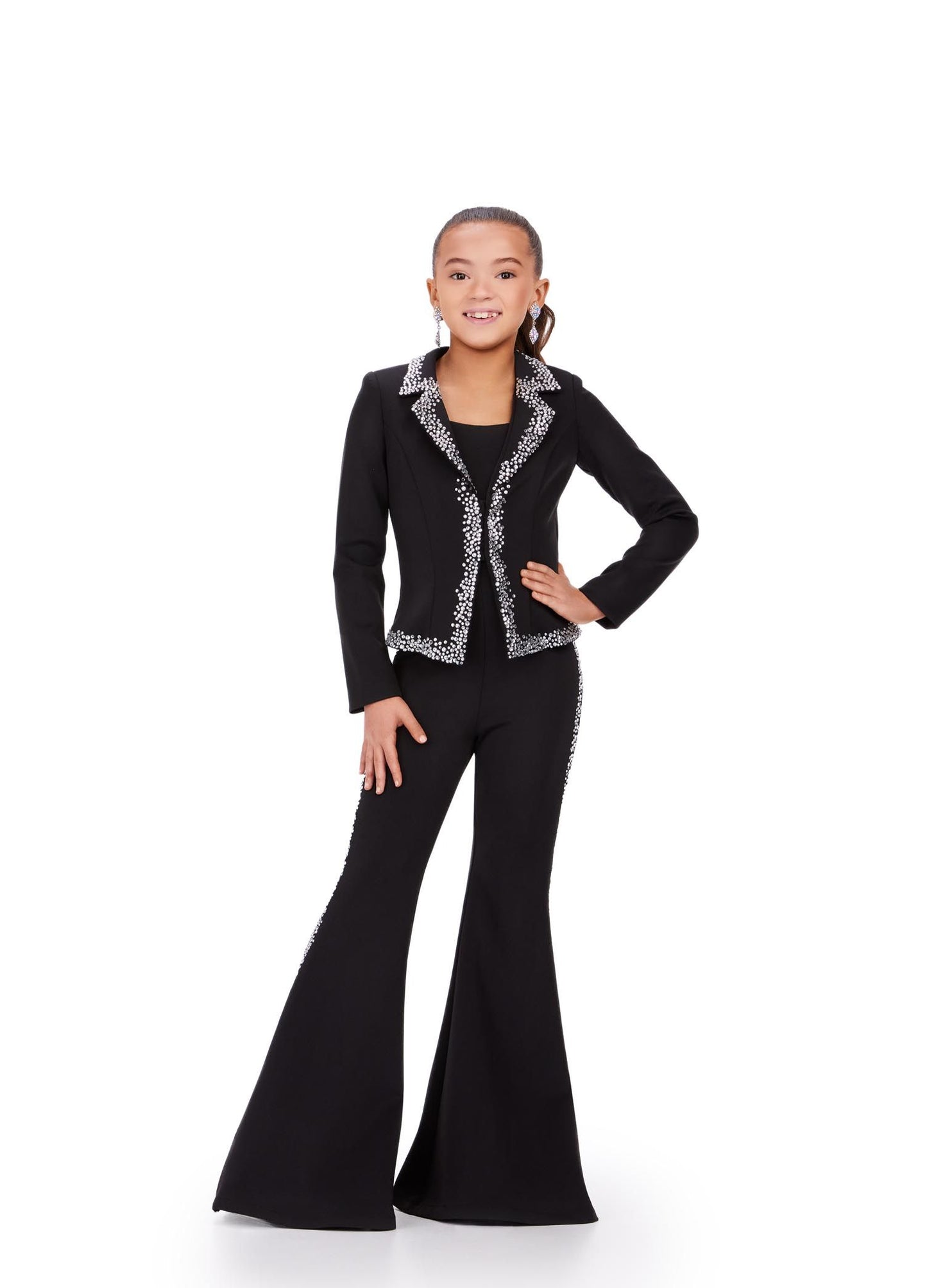 The Ashley Lauren Kids 8209 Two Piece Jumpsuit Suit features bell-bottom trousers and a crystal-studded jacket for a fashionable pageant look. High-quality materials ensure long-lasting comfort and style. Strike a pose in this fun and fabulous two piece set! Made from scuba, this suit has press on stones that trim the jacket and pant legs.  Two Piece Press On Stone Trim Flare Pant Legs Jumpsuit Sizes: 2-16 Colors: Black, Fuchsia, Royal Blue