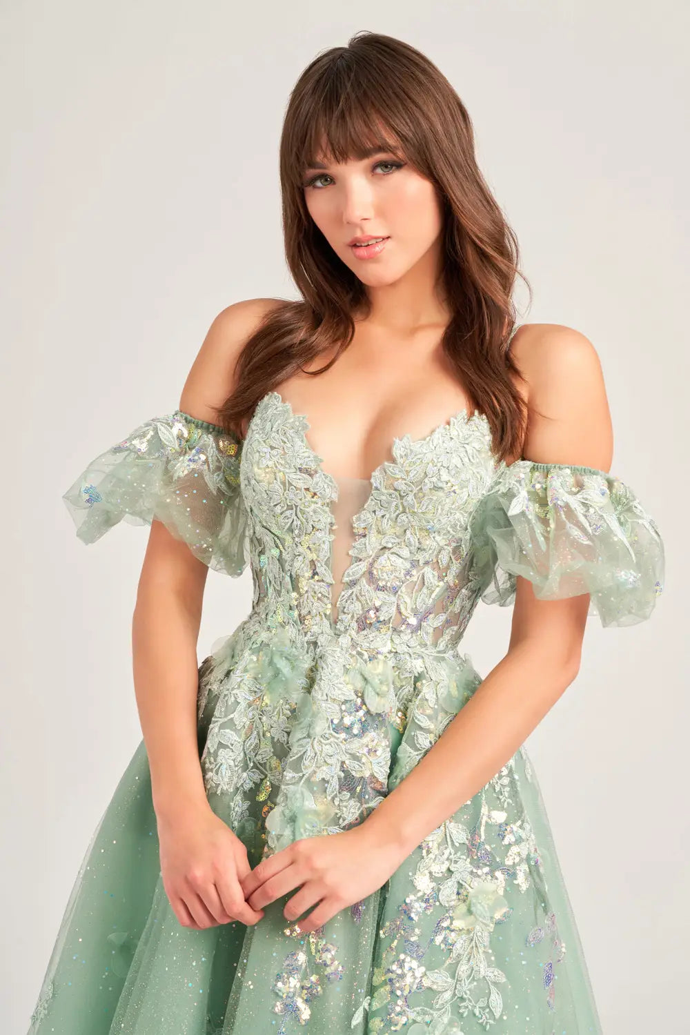 The Ellie Wilde EW35205 Prom Dress combines sheer sequin lace with a corset top and A-line silhouette, creating a stunning and shimmering gown. The puff sleeves add a touch of glamour, making this dress perfect for any prom or formal event. Pockets  Sizes: 00-20  Colors: Sage, Ice Blue