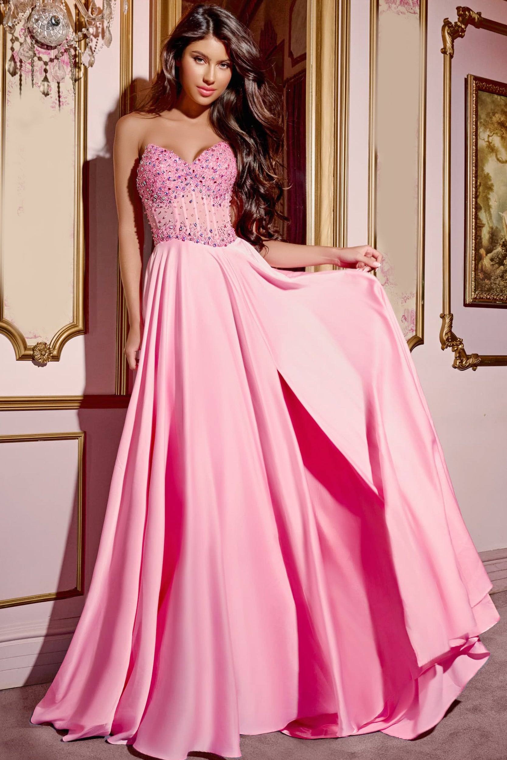 This Jovani D6021 floor-length gown features a structured sweetheart neckline, offering a flattering silhouette with its sleeveless design. The bodice is intricately embellished with scattered rhinestone accents that provide a delicate yet detailed appearance. The back of the dress is fitted and closed. The A-line skirt flows seamlessly from the fitted bodice into a voluminous chiffon train, creating graceful movement. The full-length chiffon skirt has a soft, flowing drape that enhances the dress’s airy ae