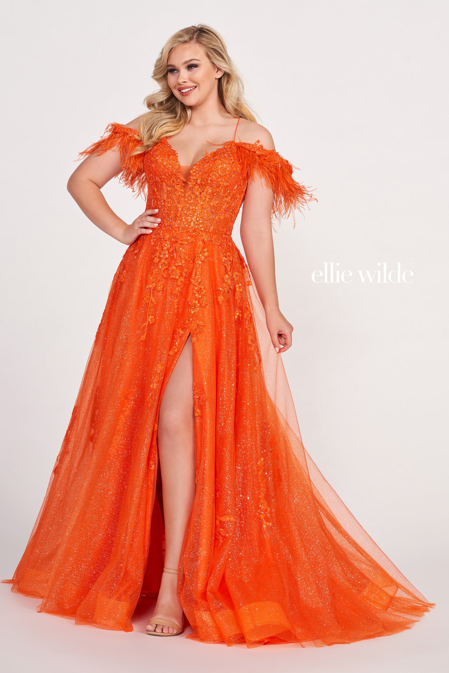 The Ellie Wilde EW34066 is a stunning A-line gown with a sheer sequin corset and feather off-the-shoulder detail. Boasting a dazzling shimmer finish and dramatic slit, this exquisite dress will make you the belle of the ball.  Sizes: 00-16  Colors: ORANGE, RED, PERIWINKLE, IRIS