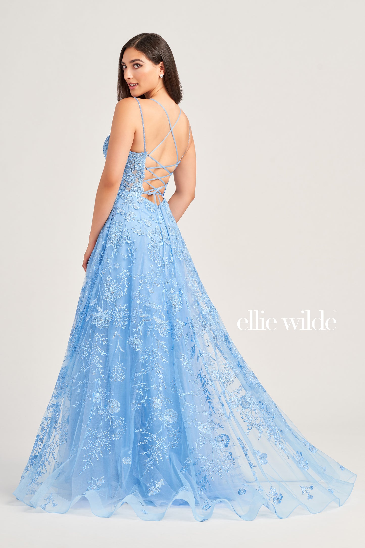 This Ellie Wilde EW35012 Formal Gown is the perfect blend of style and comfort. Crafted with beautiful embroidered tulle, lace, and stone accents, this dress features a long length, scoop neckline, and A-line silhouette. Practical and eye-catching, this gown has pockets, a high slit, and a lace-up back, all draped on a flattering natural waistline. A perfect pick to shine in style at your next event.  COLOR: MAGENTA, EMERALD, STRAWBERRY, BLUEBELL SIZE: 00 - 24