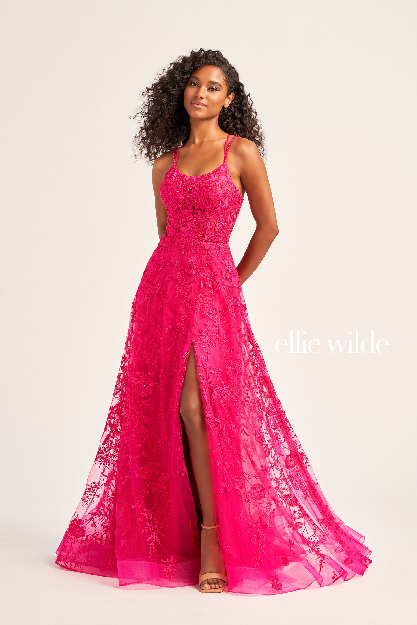 This Ellie Wilde EW35012 Formal Gown is the perfect blend of style and comfort. Crafted with beautiful embroidered tulle, lace, and stone accents, this dress features a long length, scoop neckline, and A-line silhouette. Practical and eye-catching, this gown has pockets, a high slit, and a lace-up back, all draped on a flattering natural waistline. A perfect pick to shine in style at your next event.  COLOR: MAGENTA, EMERALD, STRAWBERRY, BLUEBELL SIZE: 00 - 24