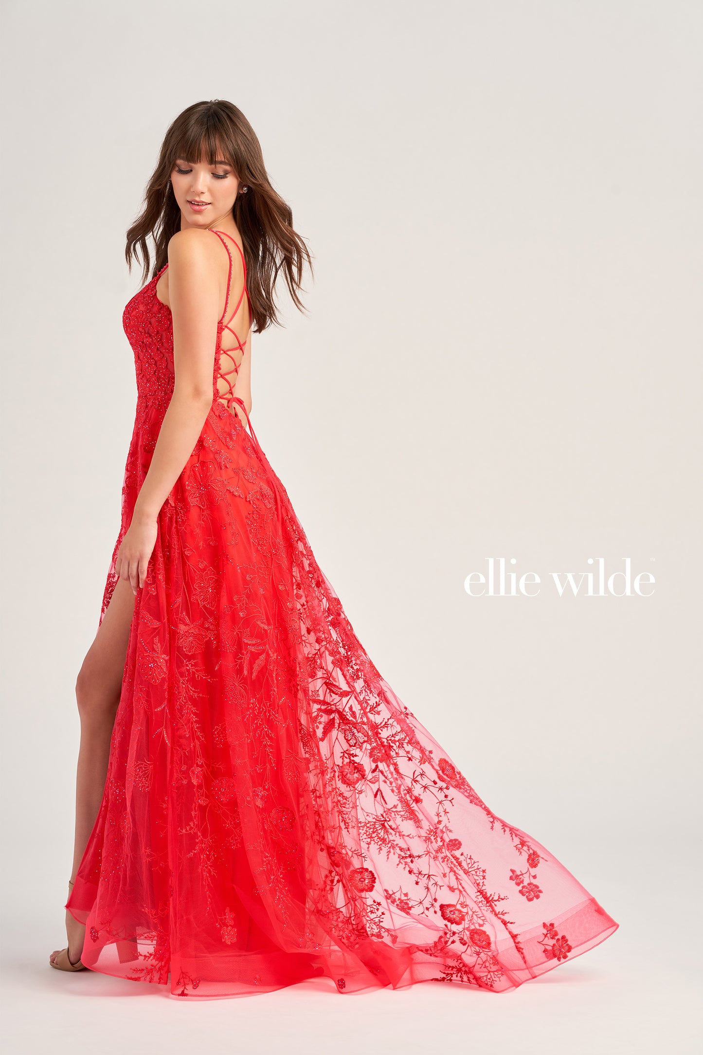 This Ellie Wilde EW35012 Formal Gown is the perfect blend of style and comfort. Crafted with beautiful embroidered tulle, lace, and stone accents, this dress features a long length, scoop neckline, and A-line silhouette. Practical and eye-catching, this gown has pockets, a high slit, and a lace-up back, all draped on a flattering natural waistline. A perfect pick to shine in style at your next event.  COLOR: MAGENTA, EMERALD, STRAWBERRY, BLUEBELL SIZE: 00 - 24