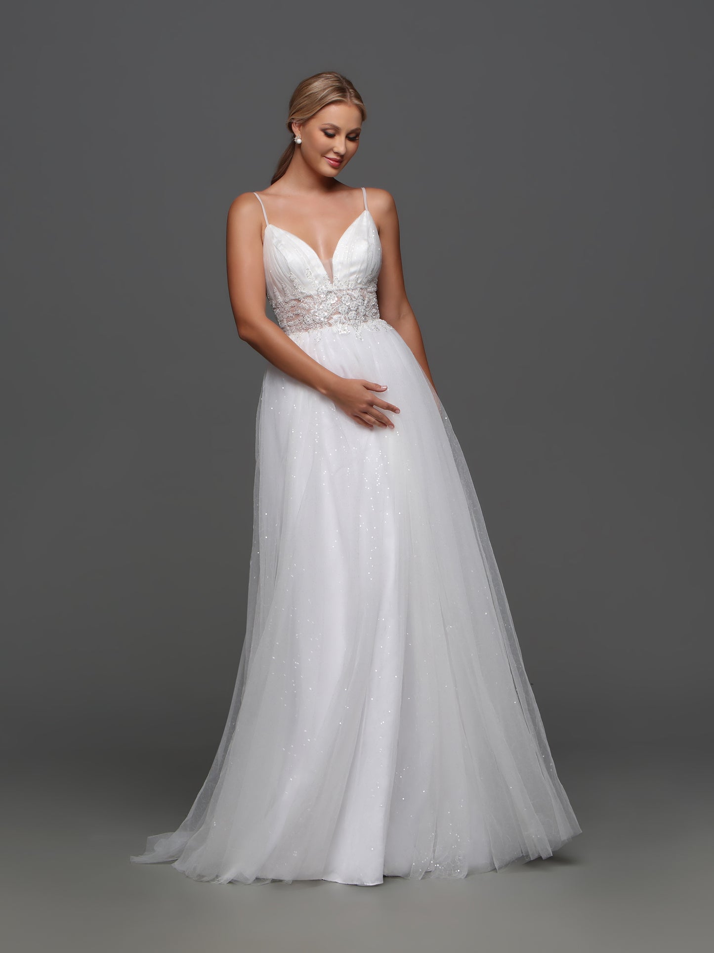 Elevate your bridal look with our Davinci Bridal F130 wedding dress. This exquisite A-line gown features intricate beading and shimmering sequins, adding a touch of glamour to your special day. The sheer bodice and V-neckline enhance your figure, while the flowing skirt creates a romantic silhouette. Be a vision of luxury and sophistication on your wedding day. Softly elegant, this A-line wedding gown has a ruched bustline and a wide sheer waistband with beaded applique. The full tulle skirt gives the dress