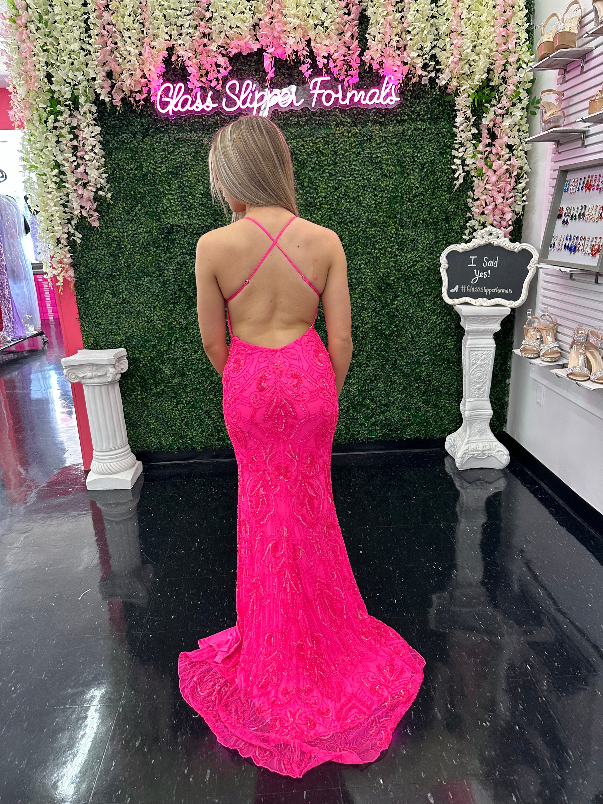 This Amarra 94143 long prom dress boasts a gorgeous neon pink hue, adorned with intricate beading for a touch of sparkle. The backless design and high front slit add a sultry touch to this formal gown, making it perfect for any special occasion. Make a statement and shine all night long.