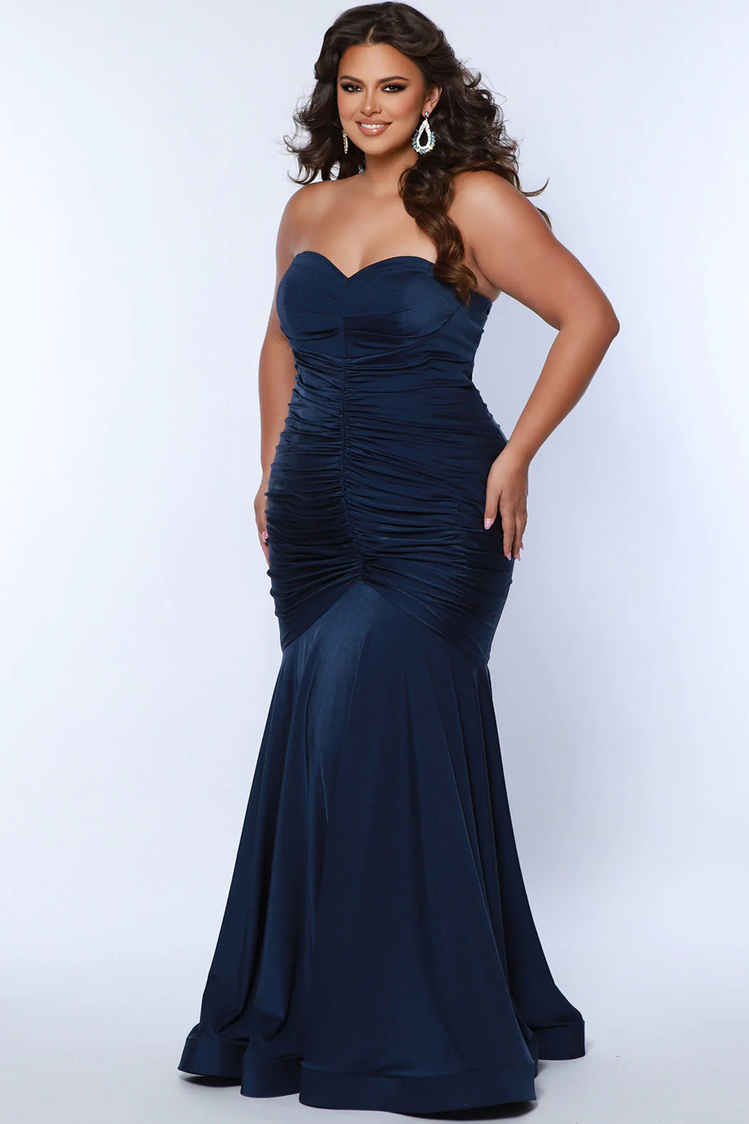 Make a statement in this luxurious Sydneys Closet SC7374 prom dress. This long, fitted gown is crafted in a mermaid silhouette, with a strapless neckline, ruching from the waistline to the floor, and a statement train. Perfect for plus size formal occasions. Look glamorous at Prom 2024 or any dressy event when you wear our Simply Ravishing plus size formal Mermaid gown. 