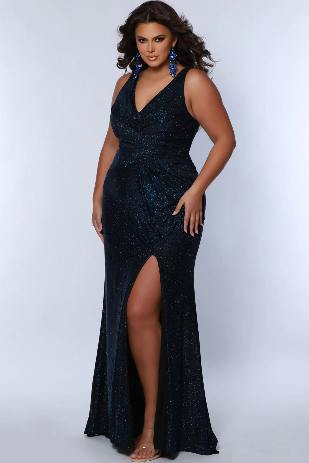 Sydneys Closet SC7376 offers a fitted plus size formal gown featuring a flattering V-neck, maxi slit skirt, and train detail for an unforgettable look. Perfect for prom or pageants. Look effortlessly elegant as a formal wedding guest or for any fancy evening that awaits you in the Late Night Sparkle plus size simple maxi dress. 