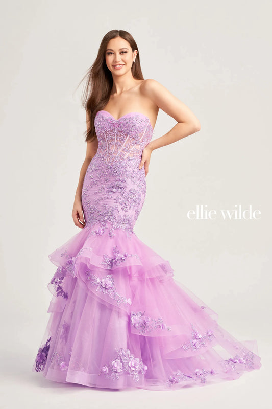 Get ready to make a statement in this Ellie Wilde EW35239 mermaid prom dress. The sheer corset lace bodice is adorned with embroidered and glitter tulle, while the ruffle layer skirt shimmers with stone accents and 3D flowers. You'll be the belle of the ball in this stunning dress.  Sizes: 00-16  Colors: Ocean Blue, Lilac, Red