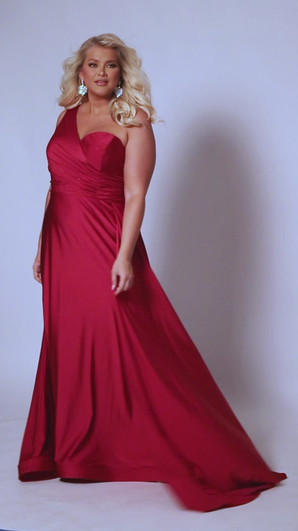 Experience elegance and glamour in the SC7377 gown from Sydneys Closet. This A-line over skirt dress features a one shoulder strap, perfect for your next special event or formal occasion. The full train adds a beautiful and regal finish to the look. Plus size available for up to size 24. Get ready to be the woman who turns heads at Prom 2024 or any special occasion evening event in the Simple and Sophisticated formal dress designed by Sydney's Closet.