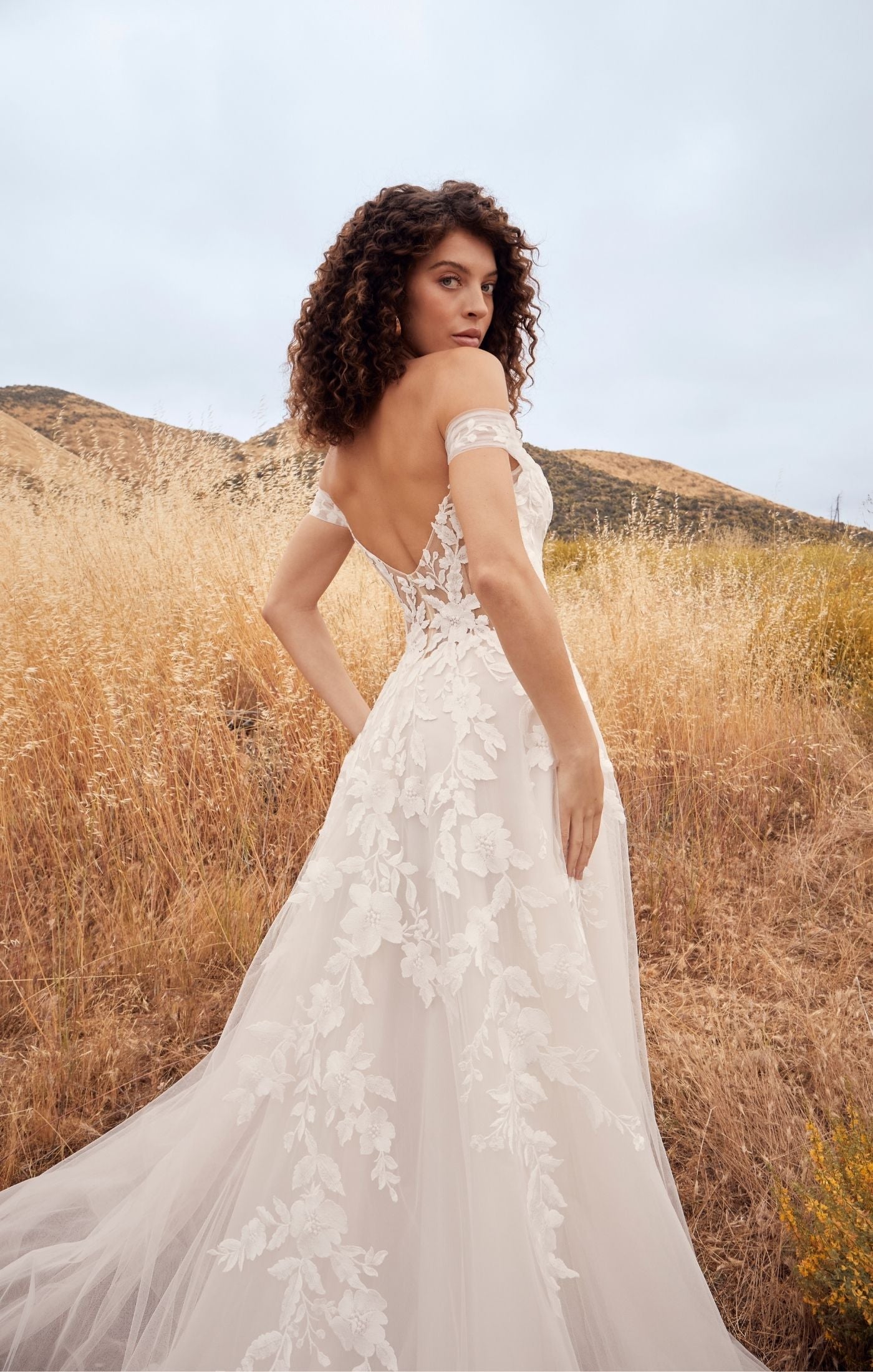 Casablanca Beloved BL433 A-Line Floral Lace Deep V-Neck Off The Shoulder Tulle Train Wedding Gown. Penny’s A-line silhouette defines her feminine form, perfectly subtle yet flattering on any size and shape. A symphony of floral lace appliques flow from her bodice, trailing down into her flattering A-line skirt