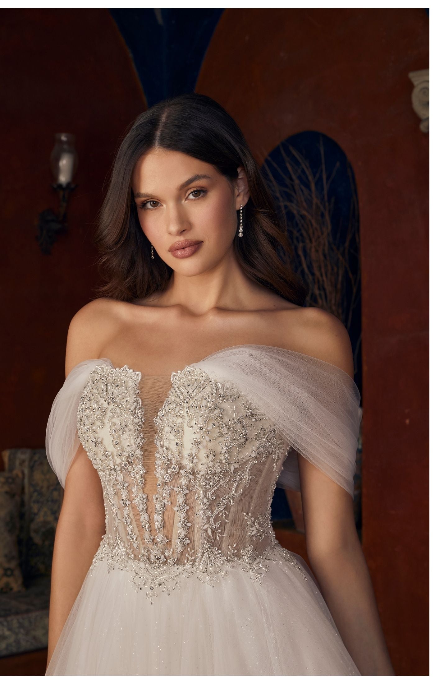 Casablanca Bridal 2547 Meline A-Line Ballgown Sheer Corset Off The Shoulder Plunging Neckline Train Wedding Gown. 2547 is a sparkling sensation, for the bride who wants to glimmer from every angle. This stunning ballgown wedding dress features an intricately beaded illusion bodice, accented by a plunging neckline and detachable off the shoulder, soft tulle straps. From tulle off-shoulder straps, to completely strapless, this versatile gown offers options for a reception change!