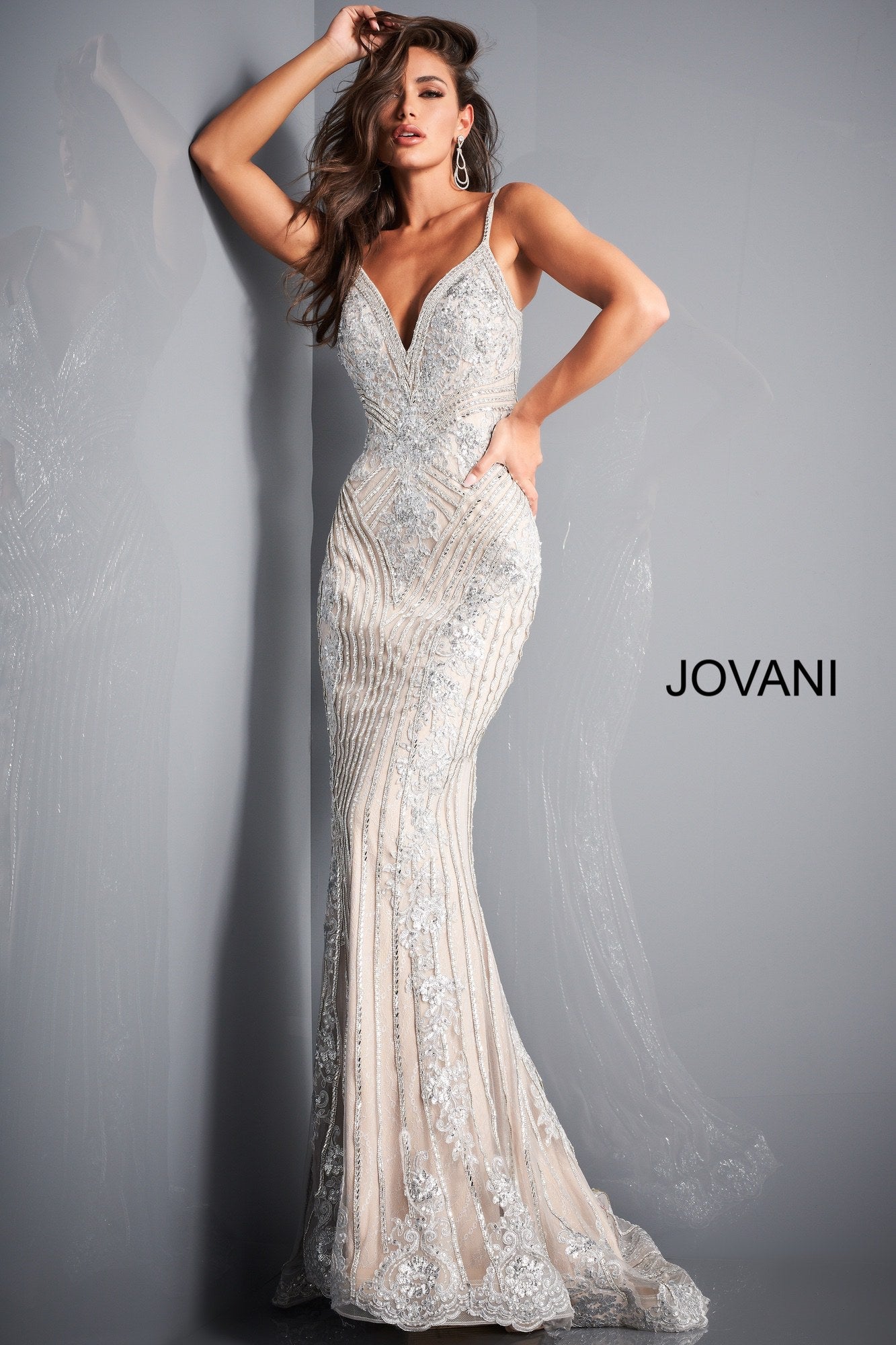 Jovani 05752 This is a silver and nude long mermaid prom dress with embellished lace throughout the evening gown.  It has a v neckline and spaghetti straps. Colors: Silver Nude  Sizes  00-24 