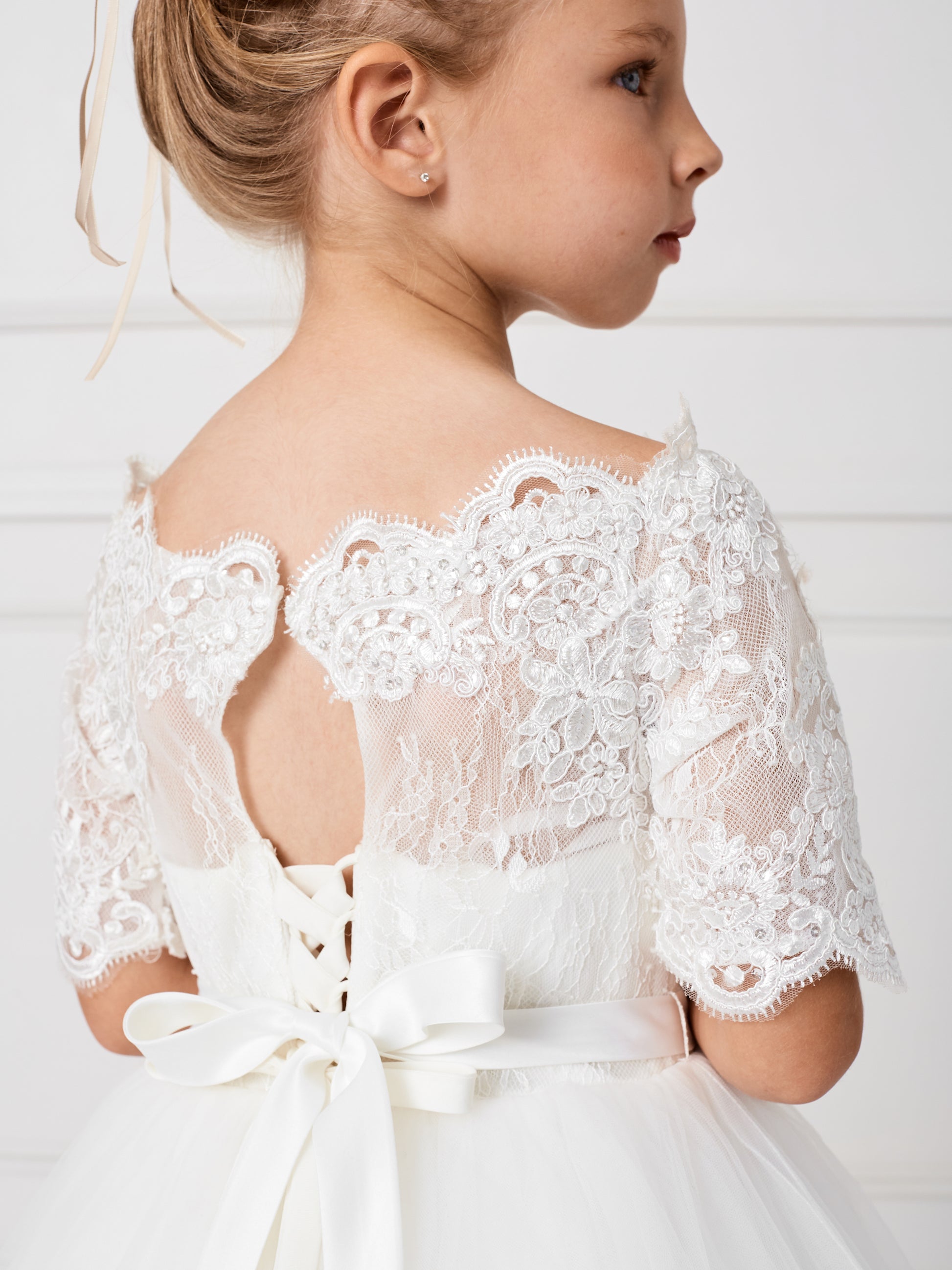 This gorgeous off shoulder dress is perfect for your little girl. The center of the dress has a simple bow at the waist.This dress features a lace peplum skirt with a long train on the back that has beautiful embroidered details. Skirt has additional netting crinoline underneath that can be puffed up if extra fullness is desired. Fully lined, zipper back, and satin sash tie-back.  Available Size: 4  Available Color: Ivory