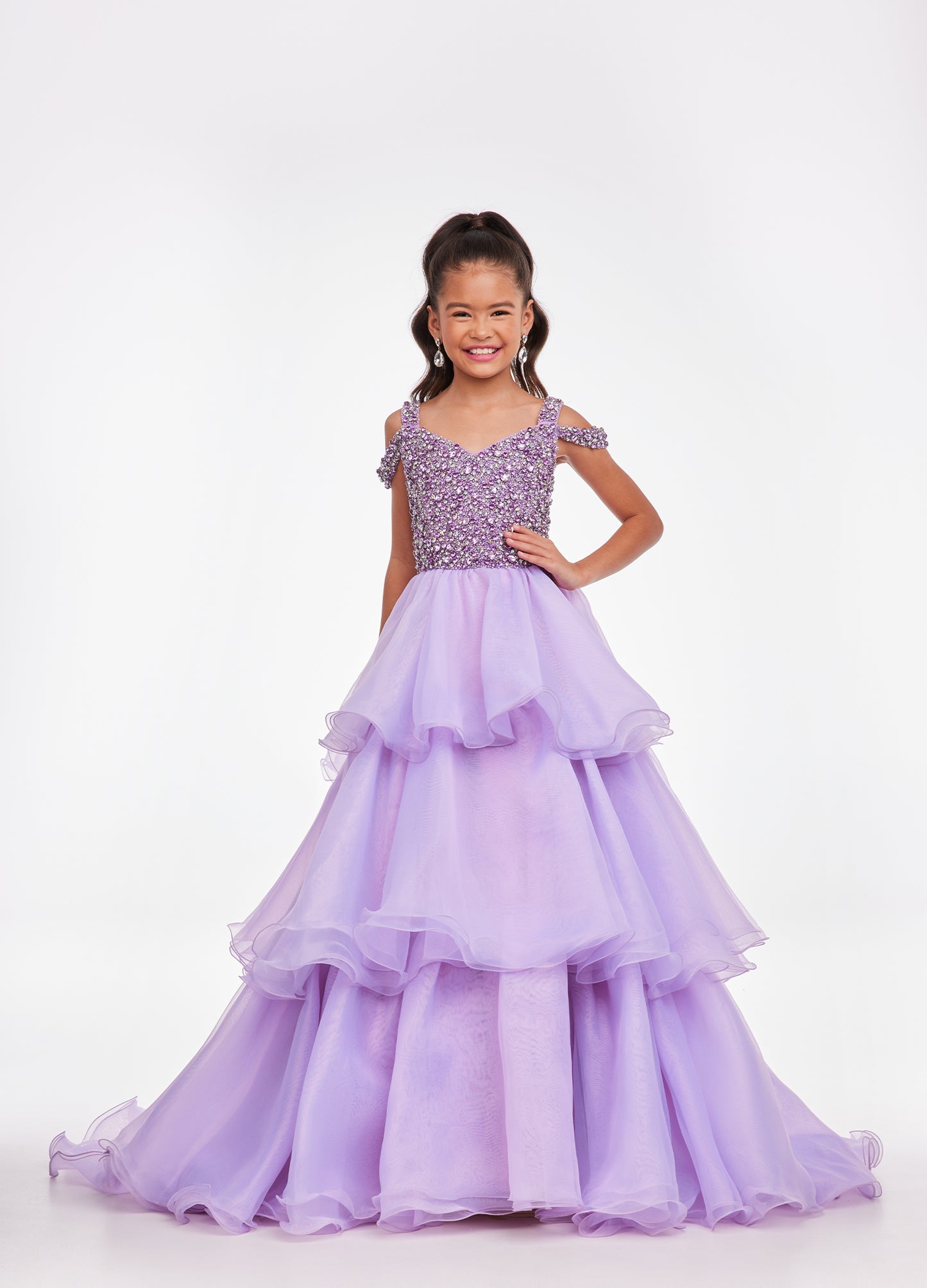 Ashley Lauren Kids 8101 Girls Pageant Dress.  The crystal encrusted bodice on this kids Pageant Gown consists of a slight V-Neckline and off the shoulder straps. The A Line multi-tiered organza ruffle skirt completes the look with a long train.   Available colors:  Hot Pink, Lilac, Turquoise