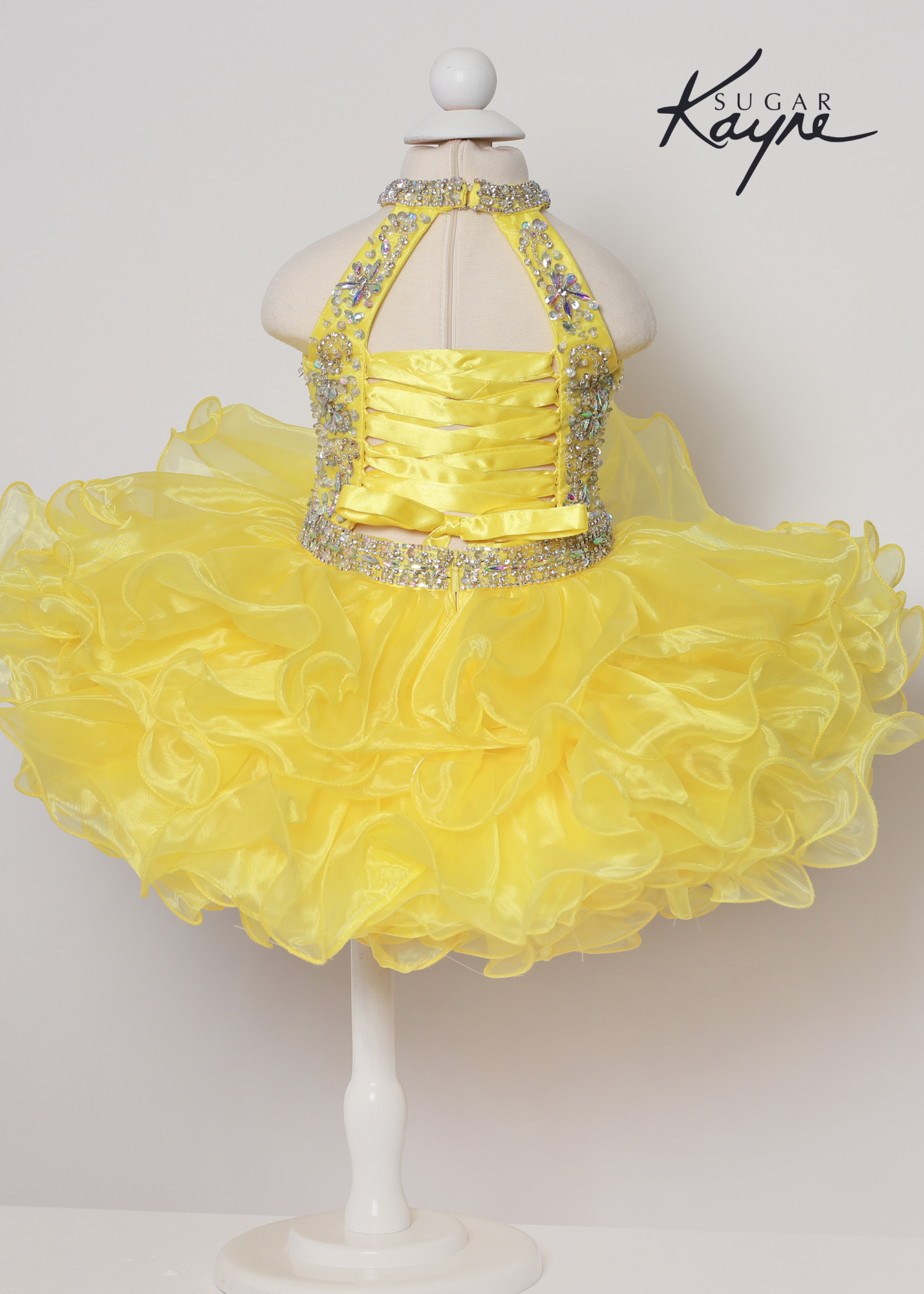 Sugar Kayne C223 Girls Baby Short ruffle Cupcake Pageant Dress Bow Halter Beaded Gown Have your little cupcake bring on all the charm in this stunning organza gown. The corset back is the perfect addition as the little one grows!  Colors: Aqua, Petal Pink, Yellow  Sizes: 0M, 12M, 18M, 24M, 2T, 3T, 4T, 5T, 6M, 6T  Fabric Organza, Satin Lining