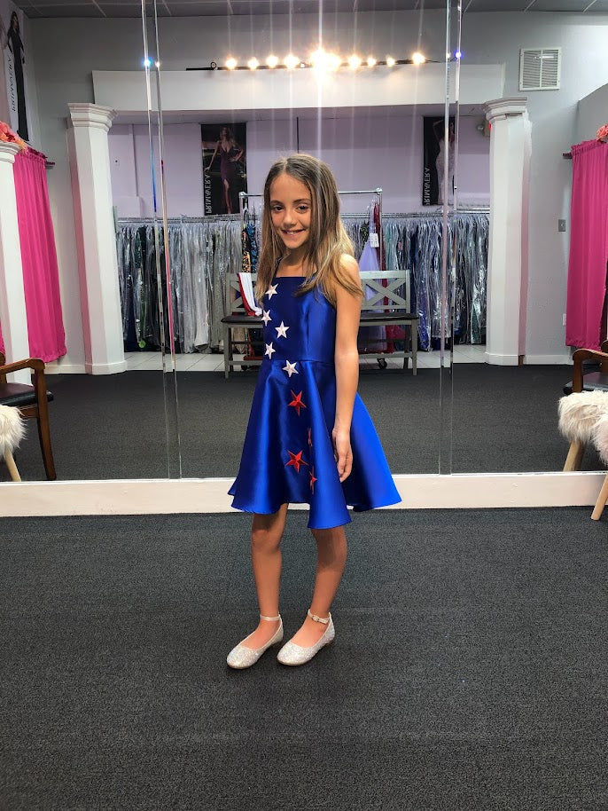 Marc Defang 5030 Red White & Blue Girls Pageant Fun Fashion Cape Detachable chiffon skirt/cape. Stars adorn he short a line dress. Perfect for Fun Fashion!  Available Sizes: 4-14  Colors: Red/White/Blue