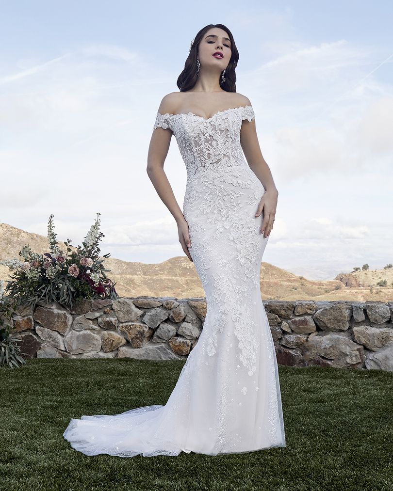 Casablanca Bridal 2419 MCKENZIE Wedding Dress Overskirt Bridal Gown off the shoulder  Beach wedding dress glam rises to a whole new level of beauty with Style 2419 McKenzie by Casablanca Bridal. Beaded lace appliques take shape as subtle stars and flowing botanicals, sitting delicately atop sequined tulle that catches the sunlight at every angle. A classic fit-and-flare silhouette hugs the natural shape of the body comfortably, while a removable organza skirt attachment with matching lace appliques, 