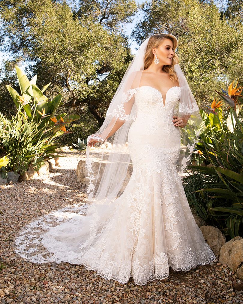 Style 2376 KARINA by Casablanca Bridal is a glamorous twist on the classic lace wedding dress. Off-shoulder sleeves transition into a classic sweetheart neckline, while floral lace swirls all throughout the fit-and-flare silhouette. The illusion back, lined with a row of subtle crystal buttons, transitions flawlessly into a gently scalloped train. A matching, two-tier cathedral length veil is available for the bride who wants to make an extra remarkable impact.  Size: 10, 14, 20  Ivory/Nude/Ivory/Silver