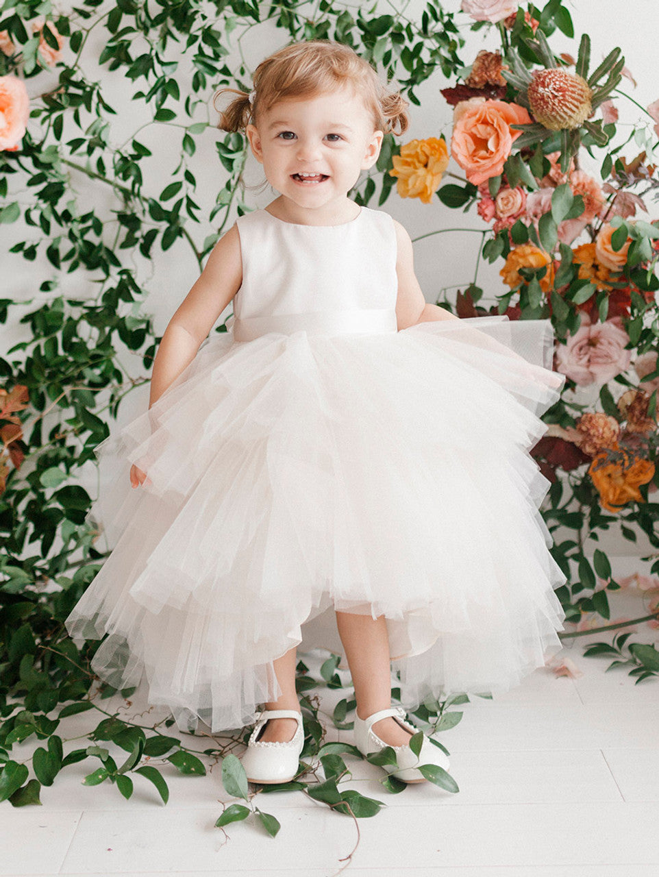 This Tip Top 5658 Girls Layered Tulle High Low Skirt Formal Dress is a perfect choice for that special day. The tulle high-low skirt, satin formal gown, and flower girl satin sash come together to create a beautiful, unique look perfect for flower girls, junior bridesmaids or formal occasions.  Sizes: 6M-16  Colors: Black, Blush, Burgundy, Eggplant, Ivory, Red, Royal Blue, White, Champagne, Lilac, Sky Blue